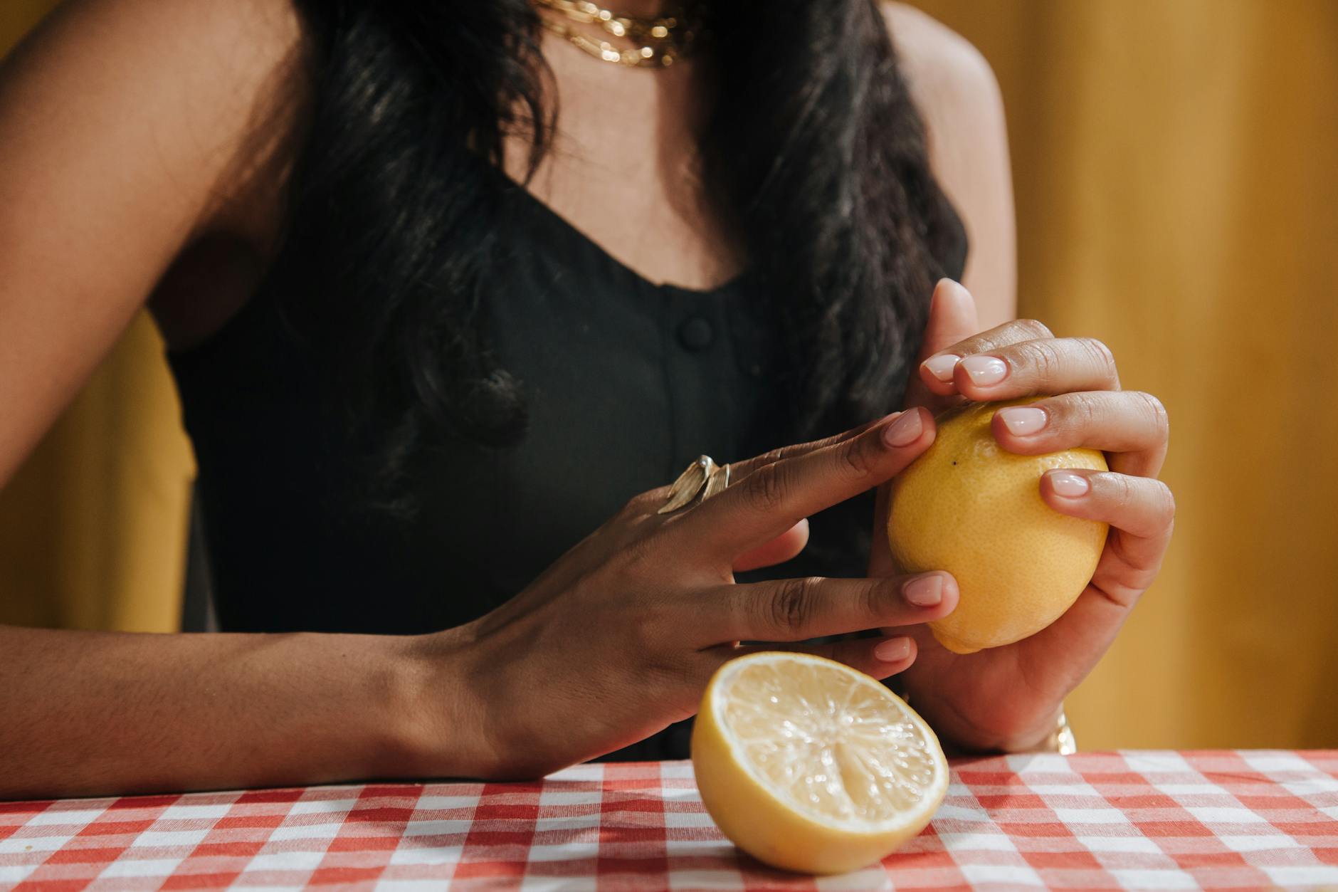 Close-up of hands holding a sleek lemon vibrator against a purple background