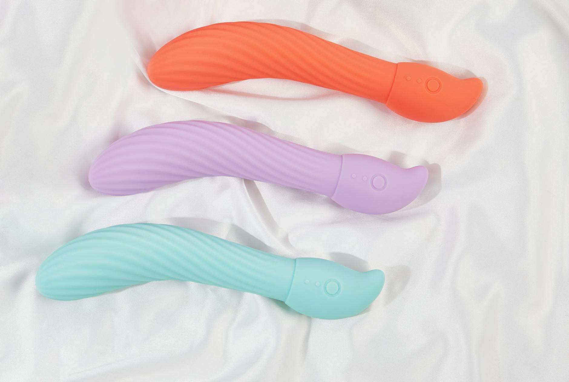 Woman thoughtfully holding blue and pink vibrators, representing openness to exploring pleasure with a partner