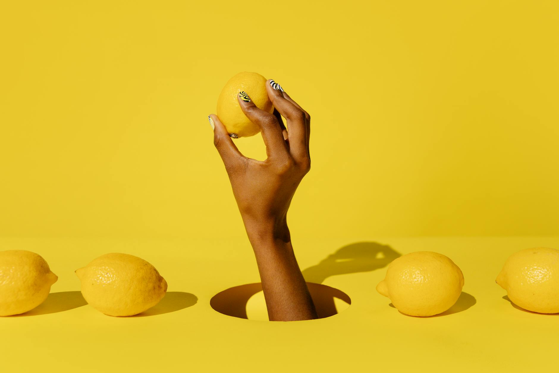 A hand holding a lemon against a yellow background, symbolizing fresh solutions for sexual wellness