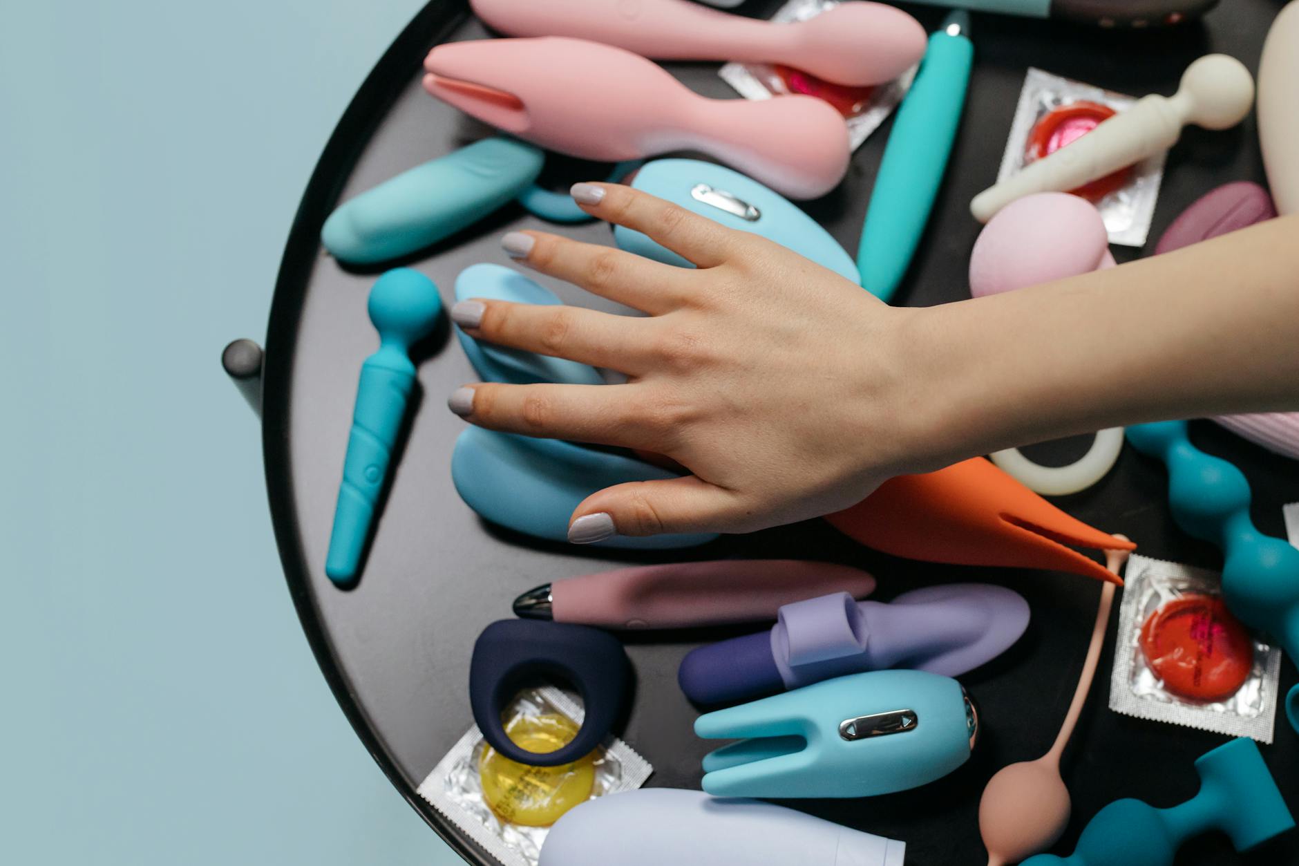 青とピンクのシリコン製バイブレーターを手に持つ女性