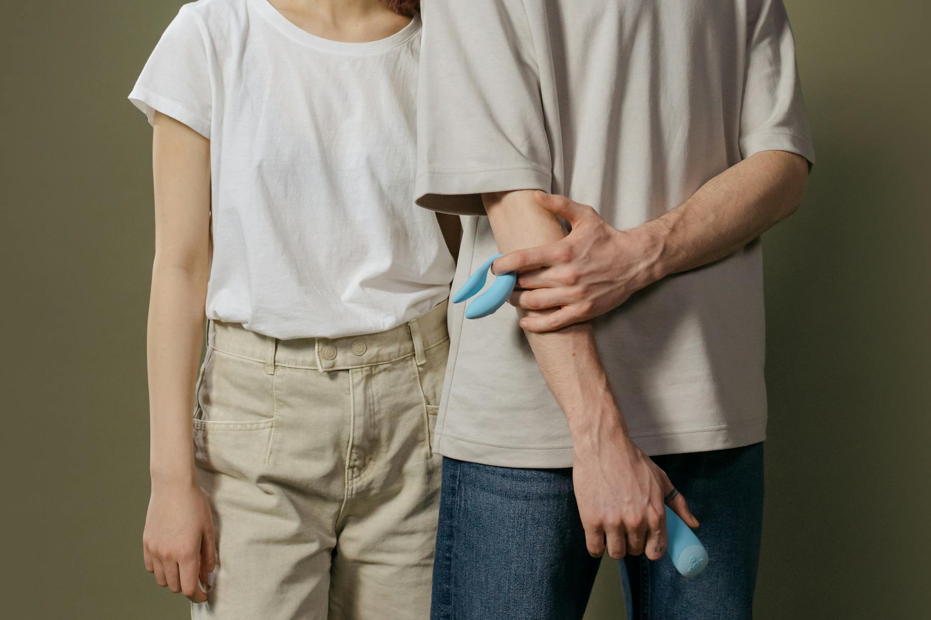 A couple holding a blue vibrator together, representing shared exploration and communication around pleasure tools.
