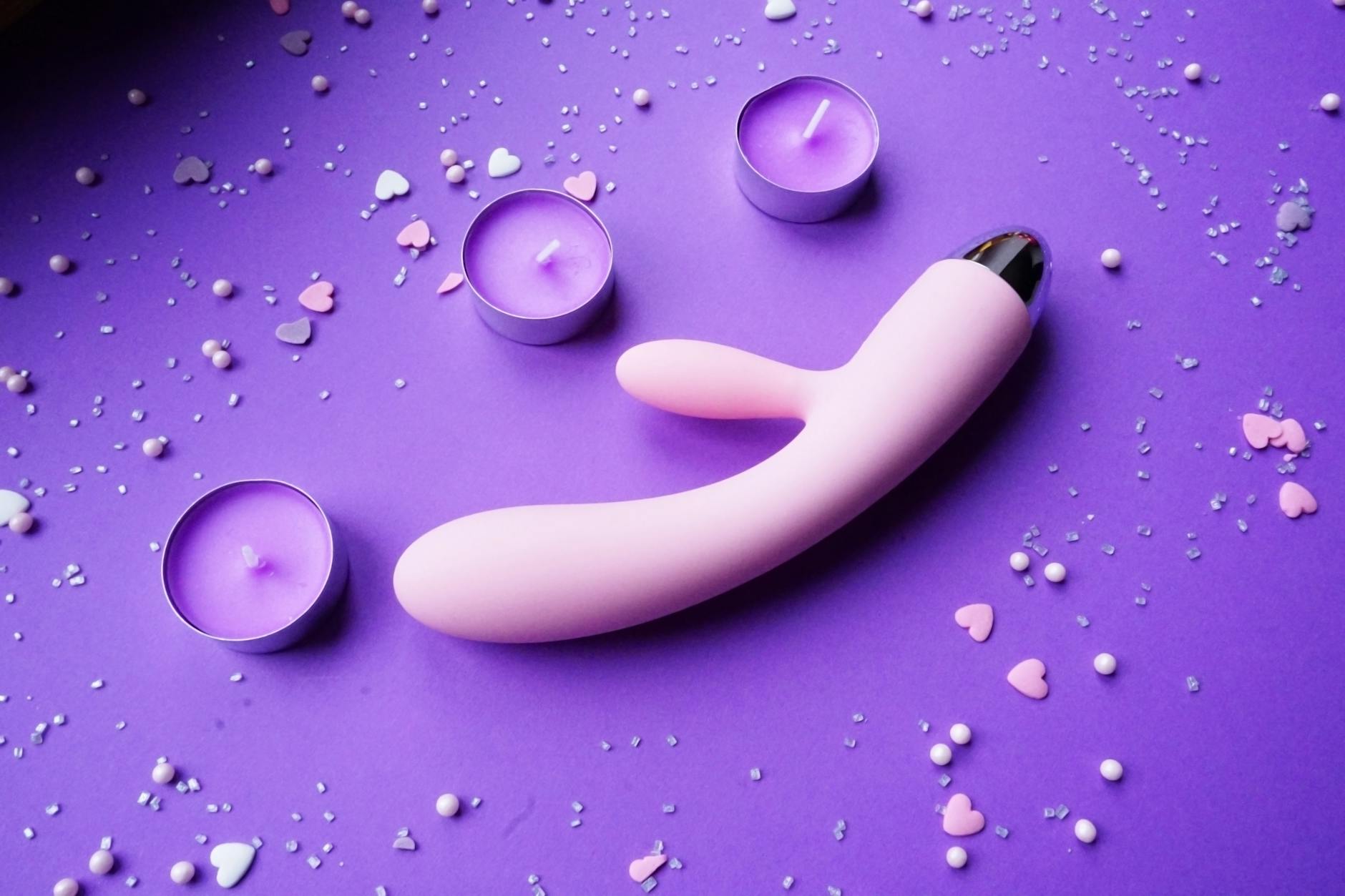 Lemon clitoral vibrator on a soft purple background with heart confetti, representing intimate wellness and pleasure rebuilding.